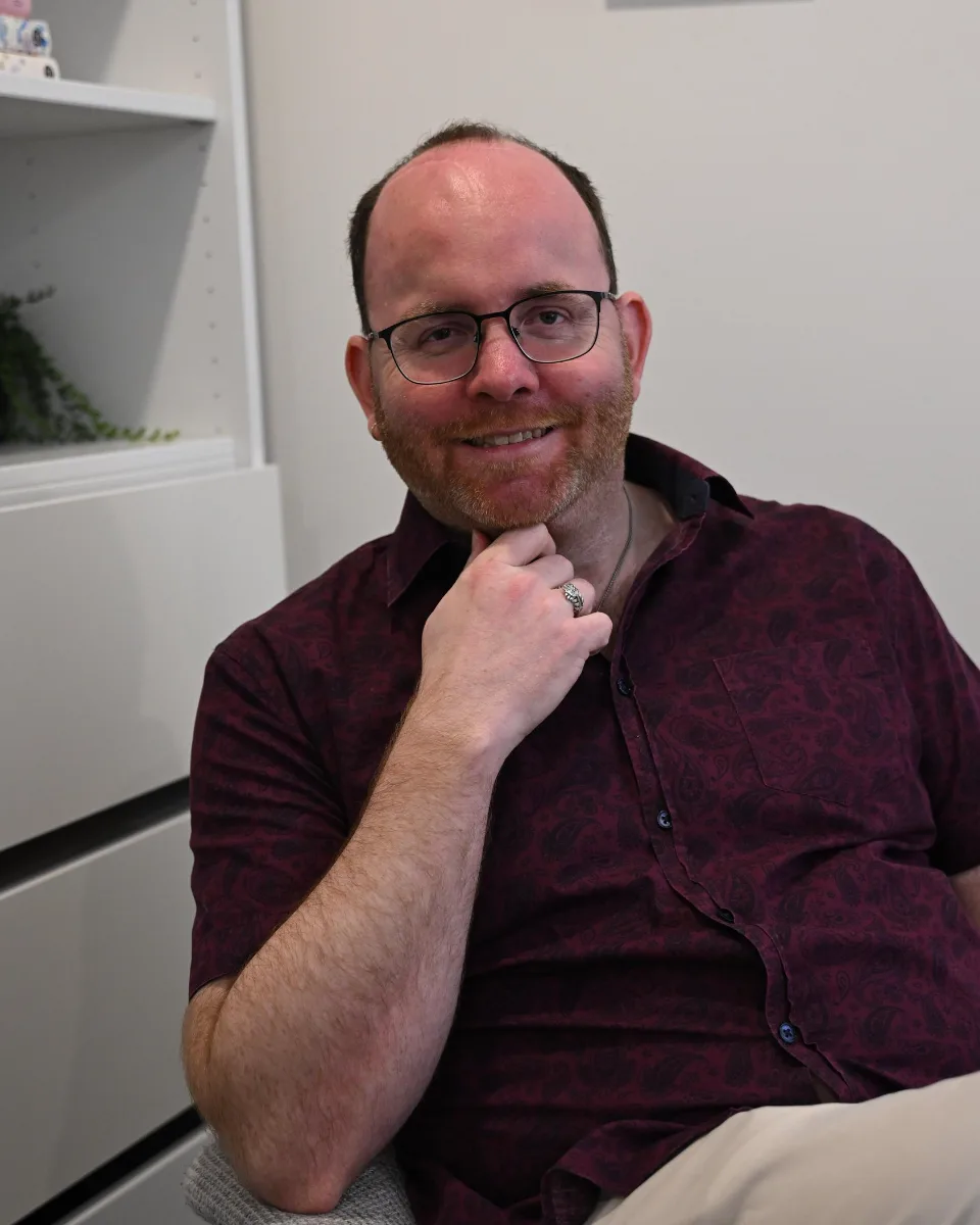 Portrait of Perry, the Peacock Visions practitioner, smiling softly in the studio