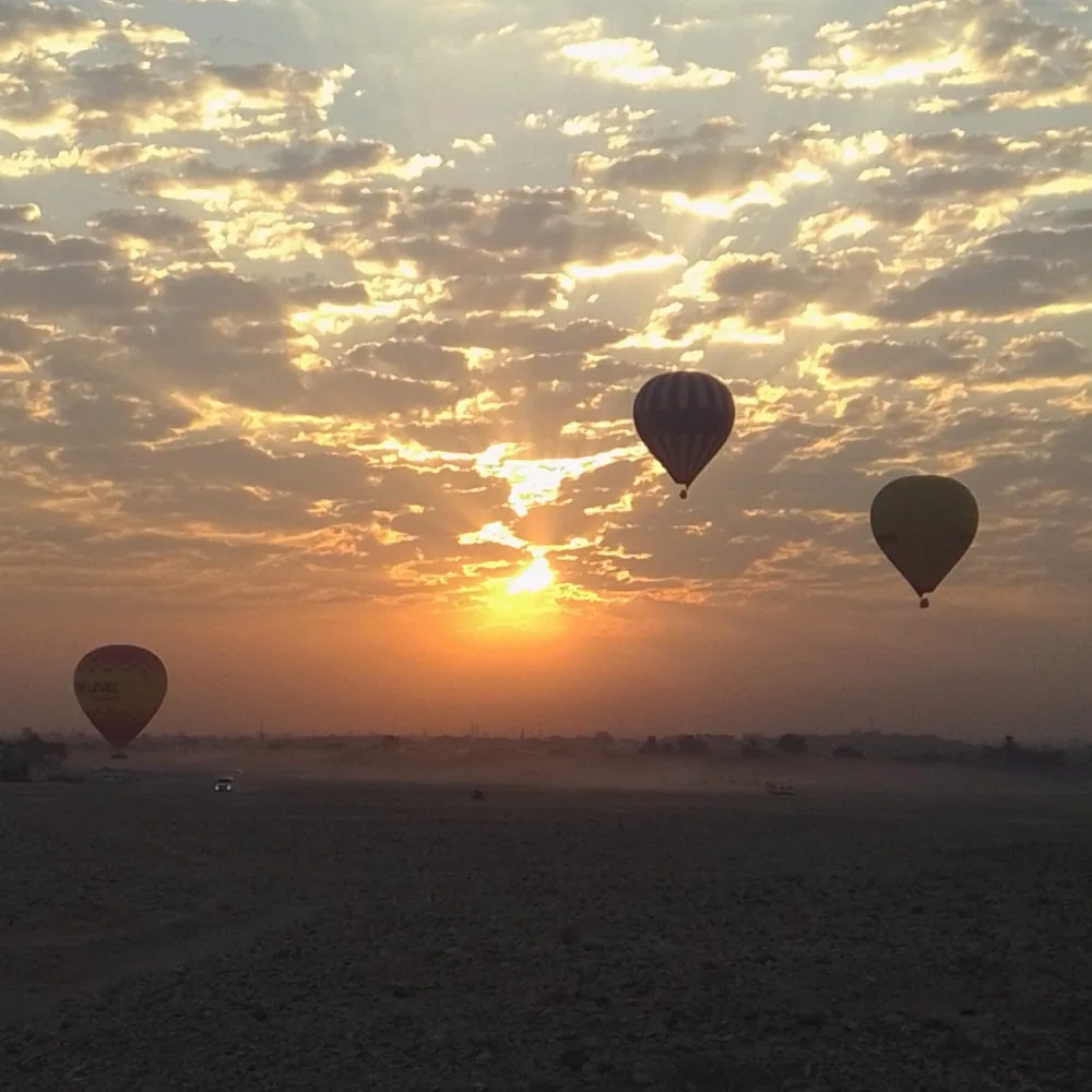 Hot air balloons drifting across a golden sunrise